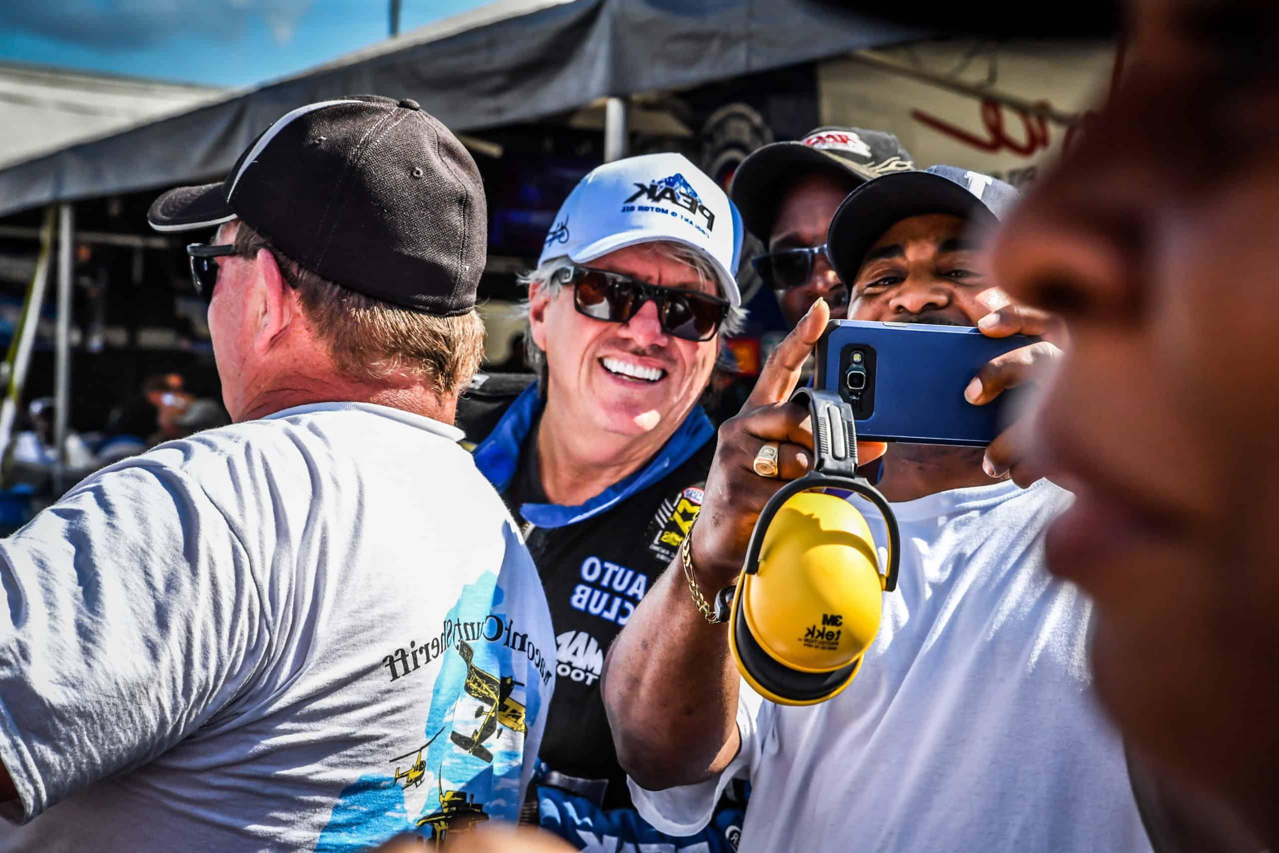 Race fans take a photo with driver, John Force